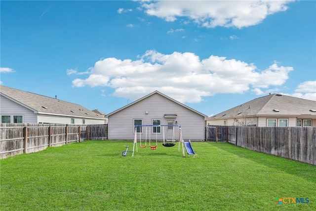 back of property featuring a yard, a playground, and a fenced backyard