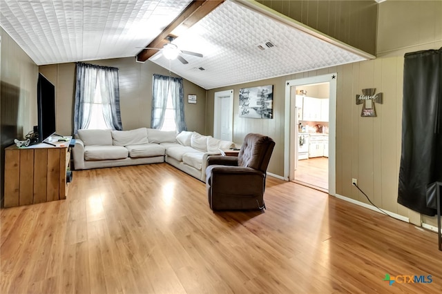 living room featuring wood walls, light hardwood / wood-style floors, ceiling fan, and lofted ceiling with beams