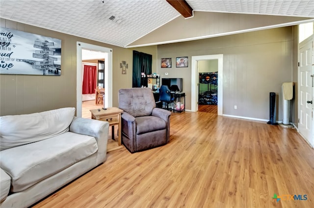 living room featuring light hardwood / wood-style flooring and vaulted ceiling with beams