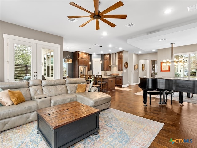 living room featuring dark wood-type flooring, ceiling fan with notable chandelier, and french doors