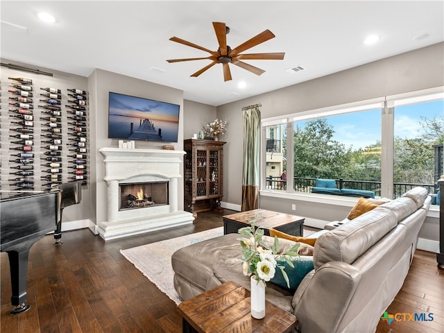 living room featuring ceiling fan, dark hardwood / wood-style floors, and a fireplace