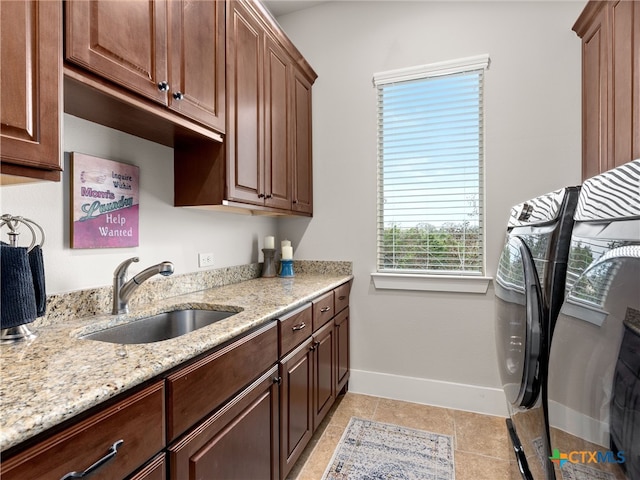 washroom with sink, light tile patterned floors, washer and clothes dryer, and cabinets