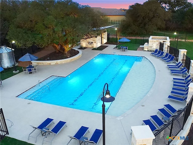 pool at dusk featuring a patio area