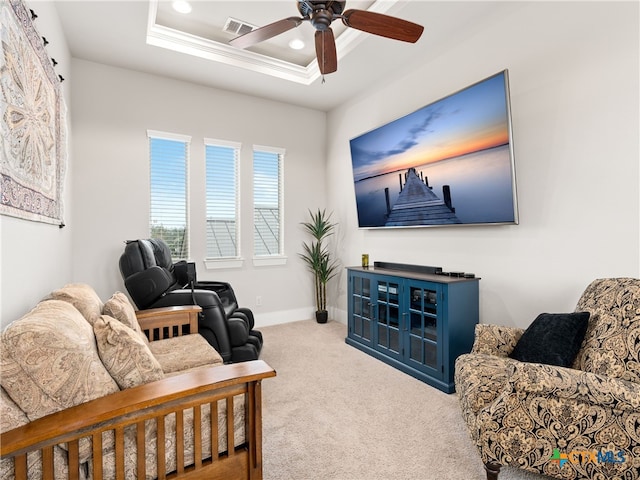 living room featuring ceiling fan, ornamental molding, carpet flooring, and a raised ceiling