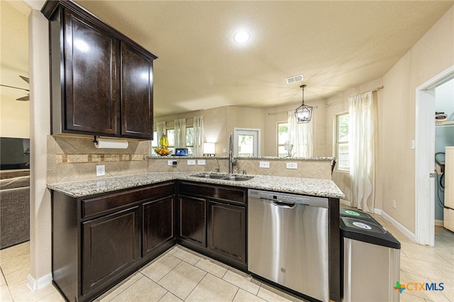 4431 Hogg, San Antonio, TX 78223 - kitchen with dishwasher, light tile patterned floors, a peninsula, dark brown cabinets, and decorative backsplash