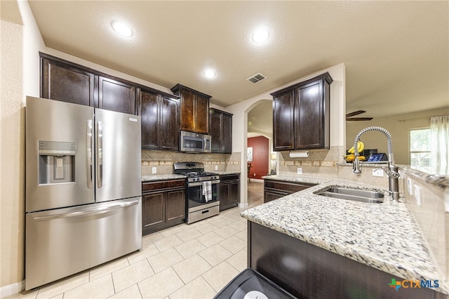 4431 Hogg, San Antonio, TX 78223 - kitchen with stainless steel appliances, arched walkways, dark brown cabinets, decorative backsplash, and light stone countertops