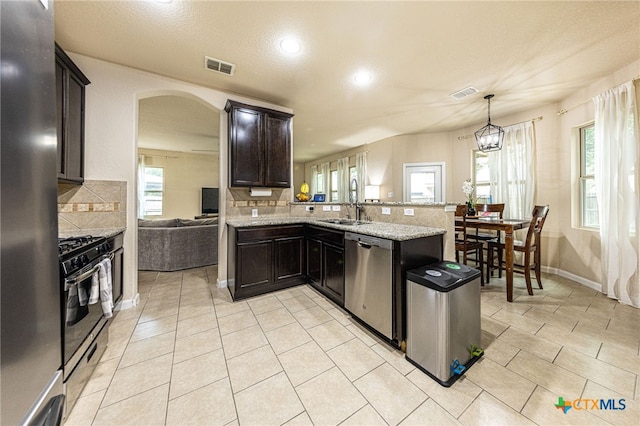 4431 Hogg, San Antonio, TX 78223 - kitchen featuring stainless steel appliances, decorative backsplash, arched walkways, a peninsula, and light stone counters