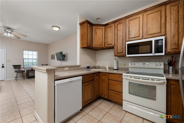 kitchen with kitchen peninsula, light tile patterned floors, sink, ceiling fan, and white appliances