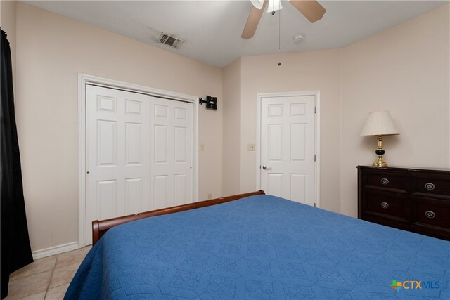 bedroom with a closet, light tile patterned floors, and ceiling fan