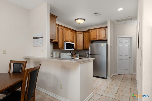 kitchen featuring kitchen peninsula, white appliances, and light tile patterned floors