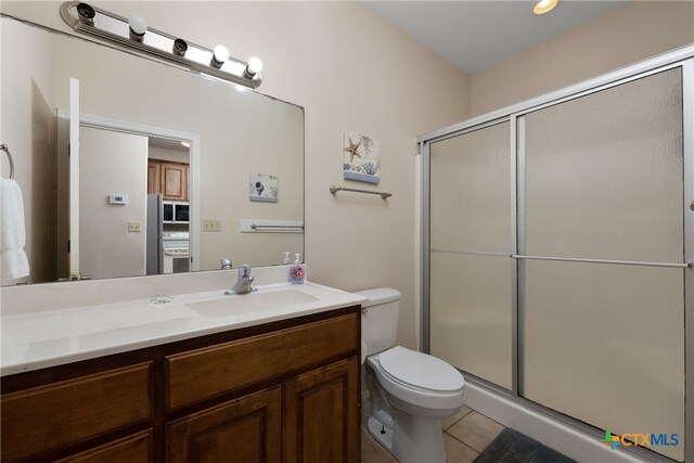 bathroom with toilet, vanity, tile patterned flooring, and a shower with door