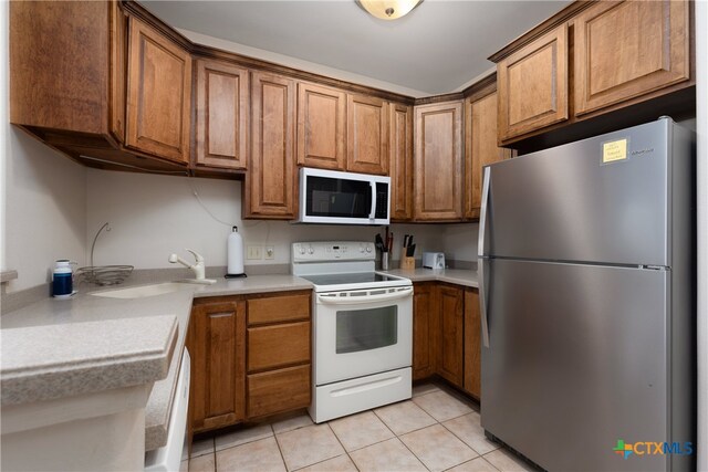 kitchen featuring white appliances, light tile patterned floors, and sink