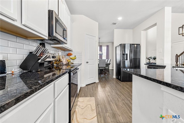 kitchen featuring visible vents, electric range, refrigerator with ice dispenser, light wood-style flooring, and stainless steel microwave