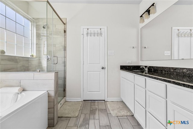 bathroom with vanity, baseboards, wood finish floors, a shower stall, and a garden tub