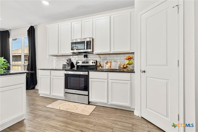 kitchen with backsplash, appliances with stainless steel finishes, light wood-style flooring, and white cabinetry