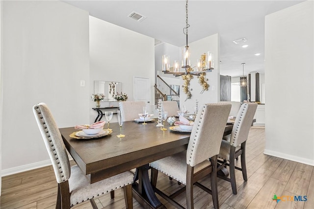 dining area featuring baseboards, visible vents, light wood-type flooring, and a chandelier