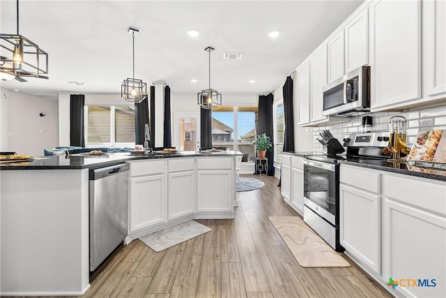 kitchen with visible vents, backsplash, stainless steel appliances, light wood-style floors, and white cabinetry