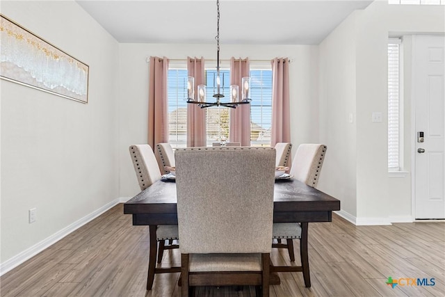 dining space with a chandelier, baseboards, and wood finished floors