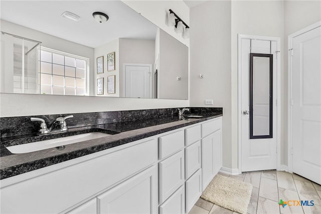 bathroom with a sink, baseboards, marble finish floor, and double vanity