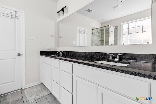 bathroom featuring double vanity, visible vents, a stall shower, and a sink