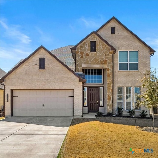 traditional home with brick siding, a front lawn, driveway, stone siding, and an attached garage