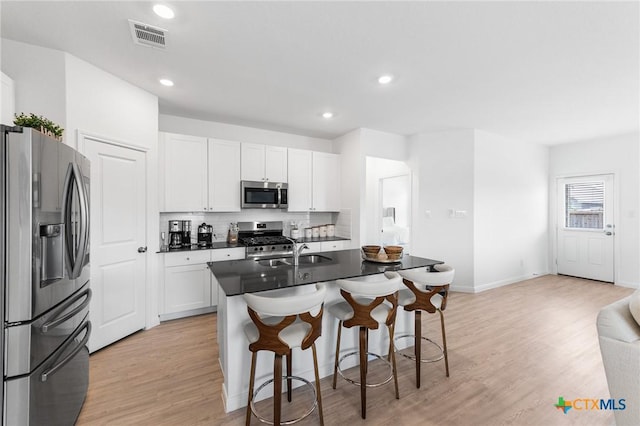 5903 Geronimo Vis, Seguin, TX 78155 - kitchen featuring appliances with stainless steel finishes, a breakfast bar area, light wood-style floors, a sink, and dark countertops