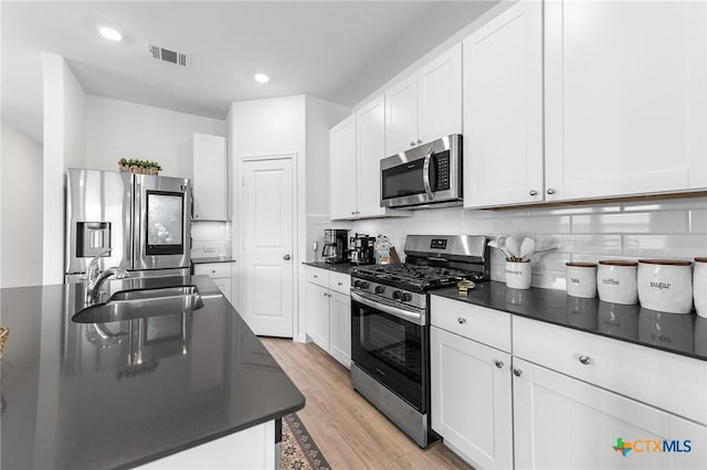 5903 Geronimo Vis, Seguin, TX 78155 - kitchen featuring appliances with stainless steel finishes, dark countertops, a sink, white cabinetry, and recessed lighting