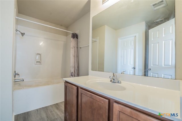 bathroom featuring wood-type flooring, vanity, and shower / bath combo