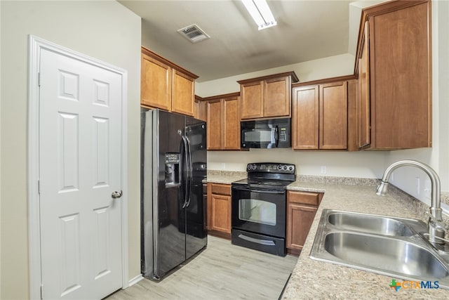 kitchen with sink, light hardwood / wood-style flooring, and black appliances