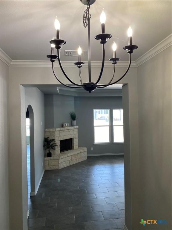 unfurnished living room featuring ornamental molding, a fireplace, a notable chandelier, and baseboards