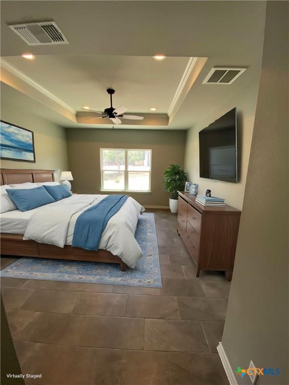 bedroom featuring a tray ceiling, visible vents, and crown molding