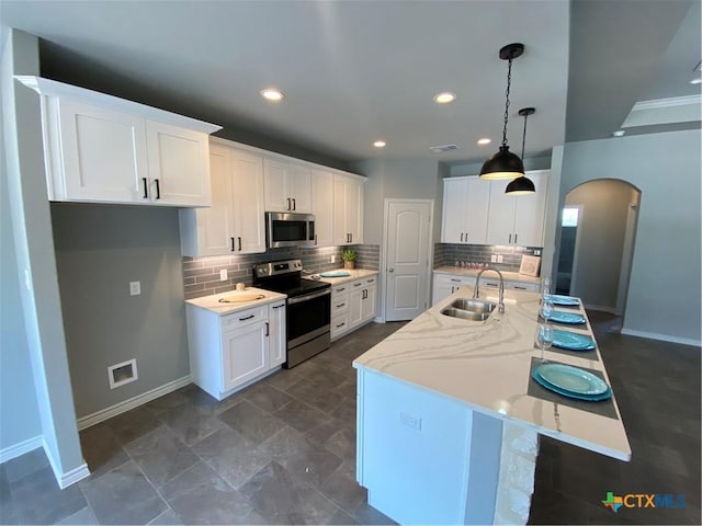 120 S Calvin Barrett, Blanco, TX 78606 - kitchen featuring stainless steel appliances, arched walkways, tasteful backsplash, a center island with sink, and white cabinetry