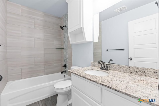 full bathroom featuring hardwood / wood-style flooring, tiled shower / bath combo, toilet, and vanity