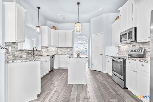 kitchen featuring white cabinetry, sink, hanging light fixtures, stainless steel appliances, and a kitchen island