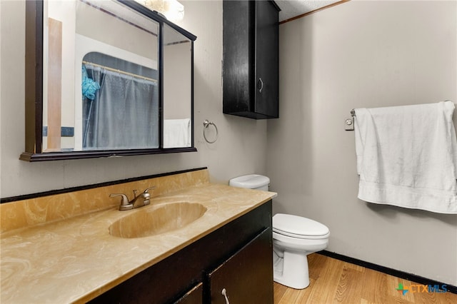 bathroom featuring a shower with shower curtain, wood-type flooring, vanity, and toilet