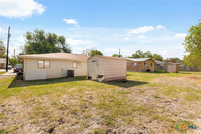 back of property with cooling unit, a storage shed, and a lawn