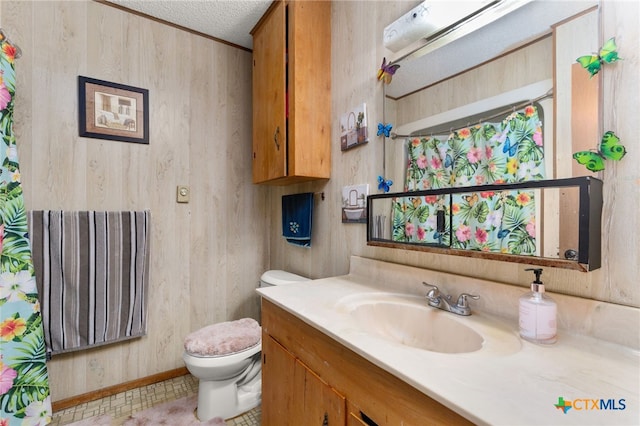 bathroom featuring vanity, a textured ceiling, wooden walls, tile patterned flooring, and toilet