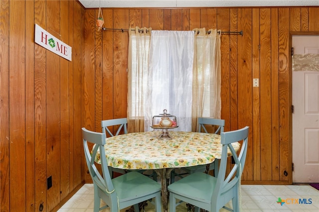 dining room featuring wooden walls and a textured ceiling