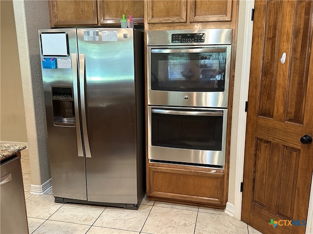 kitchen featuring light stone countertops, light tile patterned floors, and stainless steel appliances