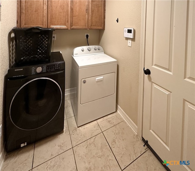 washroom with cabinets, light tile patterned floors, and washing machine and dryer