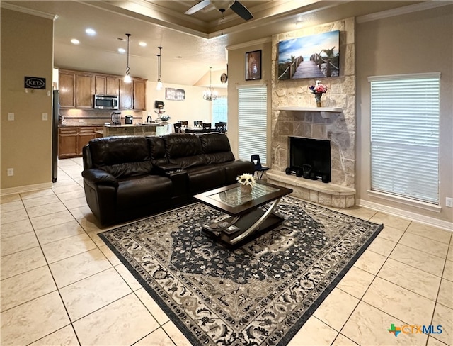 living room with a stone fireplace, light tile patterned floors, and crown molding