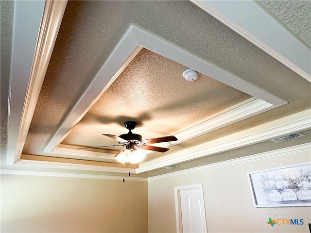 details featuring ceiling fan, a raised ceiling, ornamental molding, and a textured ceiling