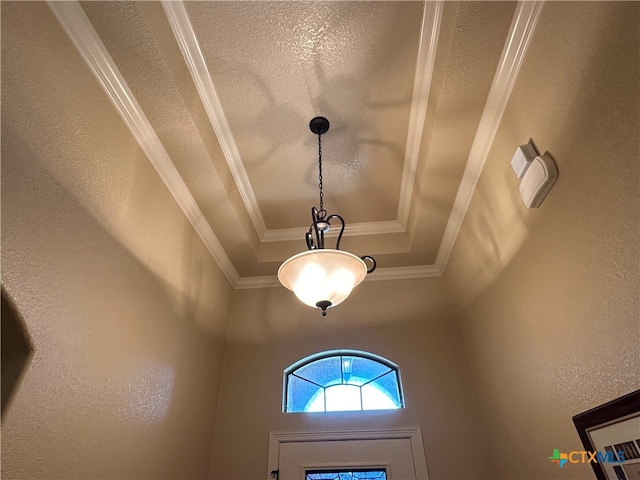 room details with a tray ceiling, a textured ceiling, and ornamental molding