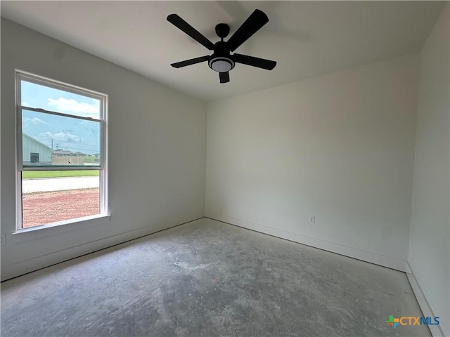 unfurnished room featuring baseboards, unfinished concrete flooring, and ceiling fan