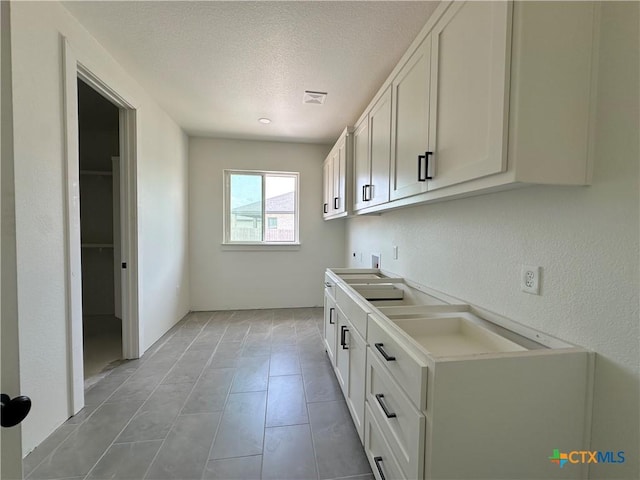 laundry area with visible vents, hookup for a washing machine, a textured ceiling, electric dryer hookup, and cabinet space
