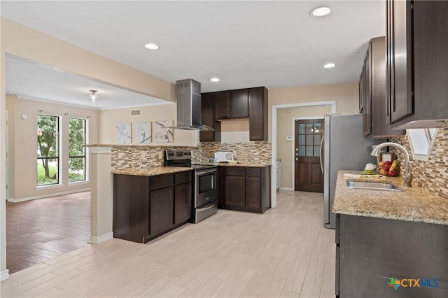 kitchen with electric stove, sink, wall chimney range hood, light stone countertops, and light hardwood / wood-style floors