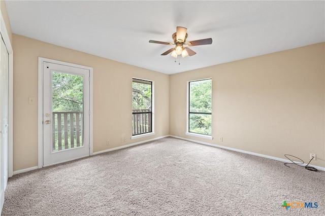 carpeted spare room featuring a wealth of natural light and ceiling fan