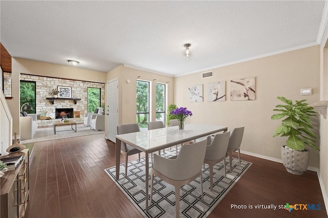 dining area featuring a textured ceiling, crown molding, a fireplace, and dark hardwood / wood-style floors