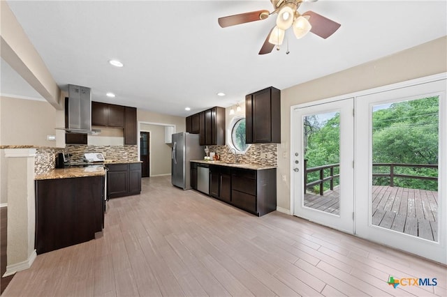 kitchen with light wood-type flooring, backsplash, dark brown cabinets, stainless steel appliances, and wall chimney range hood