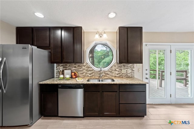 kitchen with dark brown cabinetry, decorative backsplash, sink, and appliances with stainless steel finishes